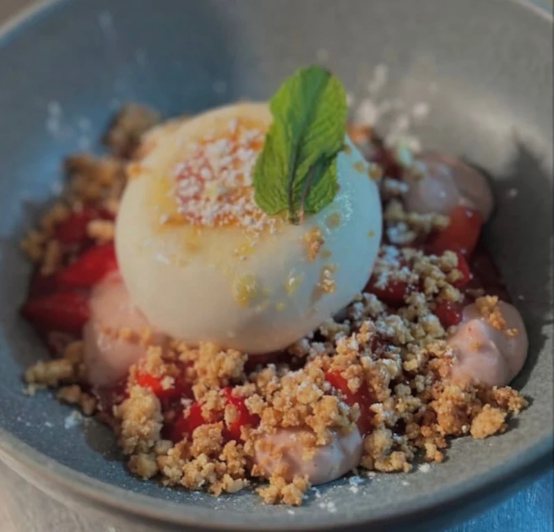 Postre: una bola cremosa con fresas, crema rosa y crujiente